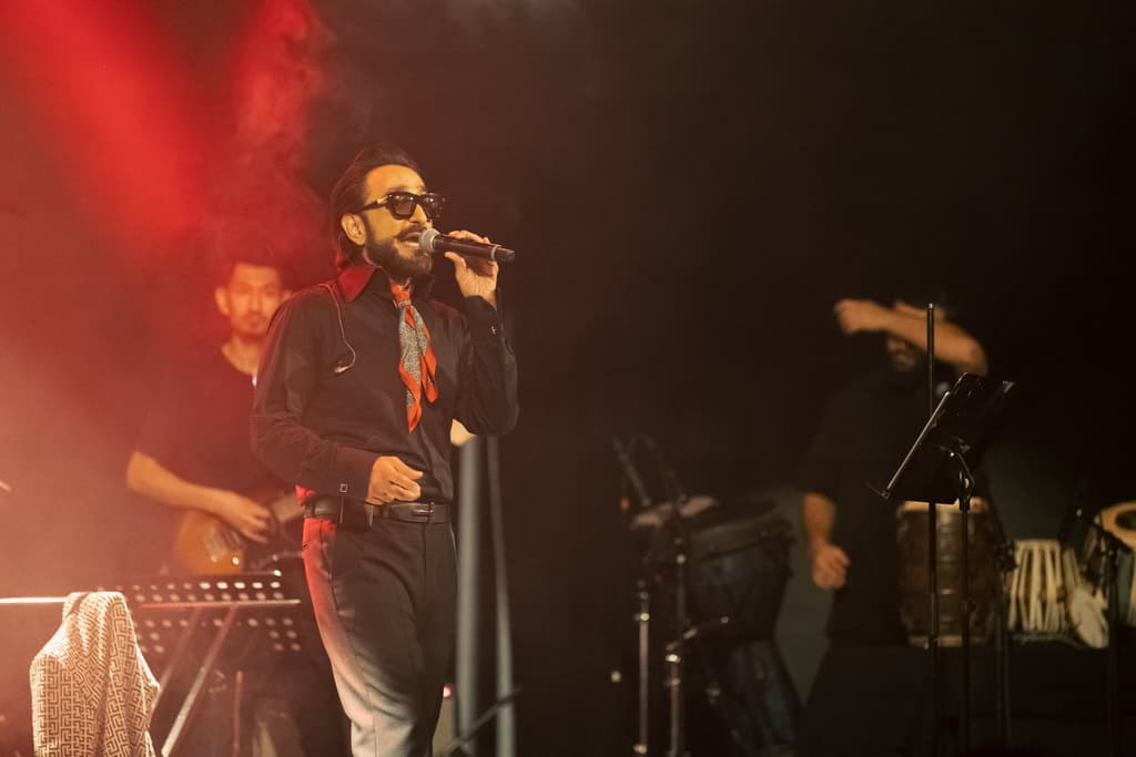 Habib Qaderi singing on stage under red stage light